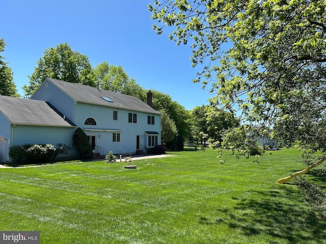 back of house with a chimney and a yard