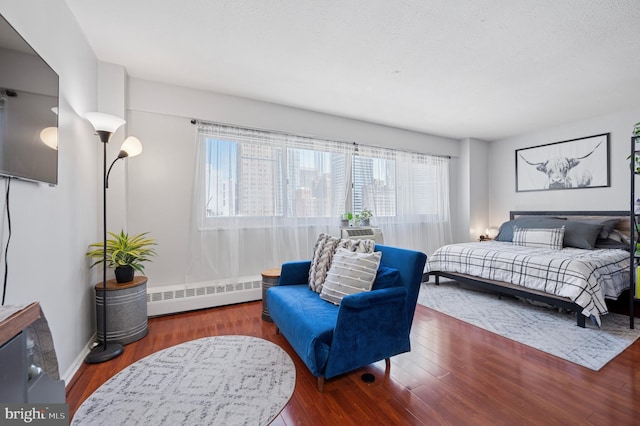 bedroom with baseboards, baseboard heating, and wood finished floors