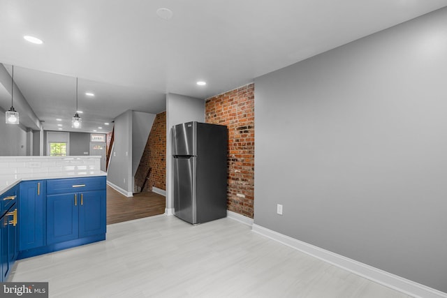 1213 Washington Blvd, Baltimore, MD 21230 - kitchen with freestanding refrigerator, blue cabinets, brick wall, light wood-style floors, and baseboards