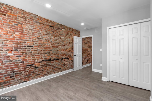 1213 Washington Blvd, Baltimore, MD 21230 - unfurnished bedroom featuring brick wall, baseboards, a closet, wood finished floors, and recessed lighting