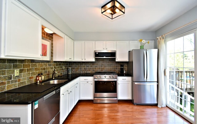 kitchen featuring a sink, tasteful backsplash, stainless steel appliances, and white cabinetry