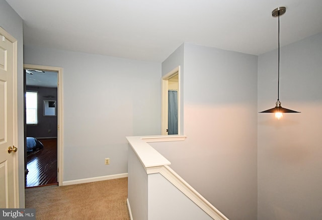 hallway with baseboards, an upstairs landing, and carpet