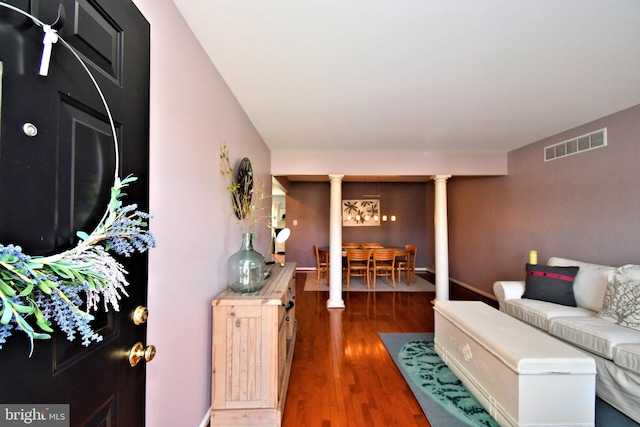 living area with visible vents, ornate columns, and wood finished floors