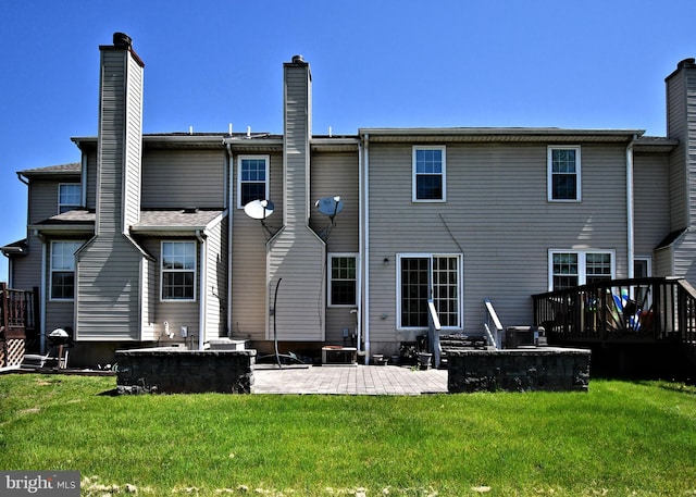 back of house featuring a chimney, a wooden deck, central air condition unit, a yard, and a patio