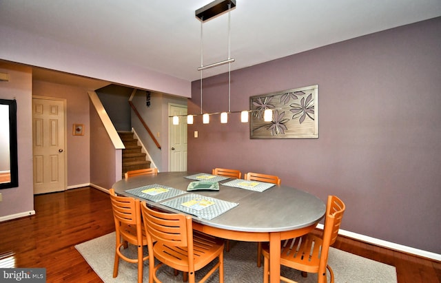 dining room featuring baseboards, stairs, and wood finished floors
