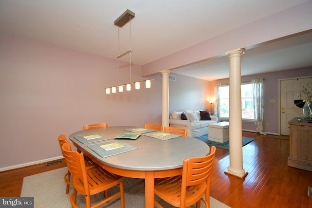 dining room with wood-type flooring, decorative columns, and visible vents