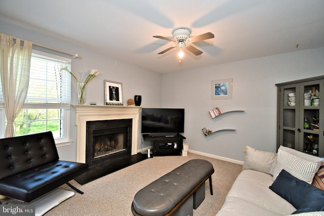 carpeted living room with baseboards, a ceiling fan, and a fireplace with flush hearth