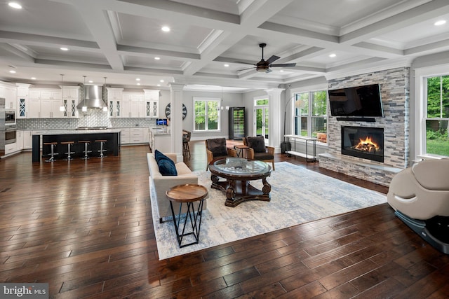 living room featuring ornate columns, coffered ceiling, plenty of natural light, and a fireplace