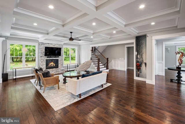 living area with ceiling fan, a large fireplace, dark wood-style floors, stairs, and a wealth of natural light