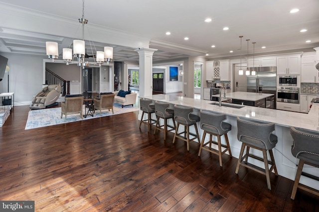 kitchen featuring dark wood-style flooring, appliances with stainless steel finishes, a sink, open floor plan, and a large island