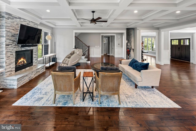 living room featuring stairway, ceiling fan, a fireplace, and coffered ceiling
