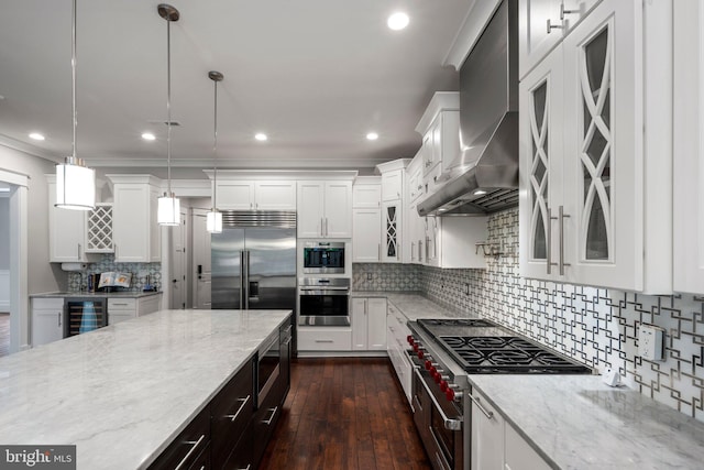 kitchen with built in appliances, glass insert cabinets, beverage cooler, wall chimney range hood, and white cabinetry