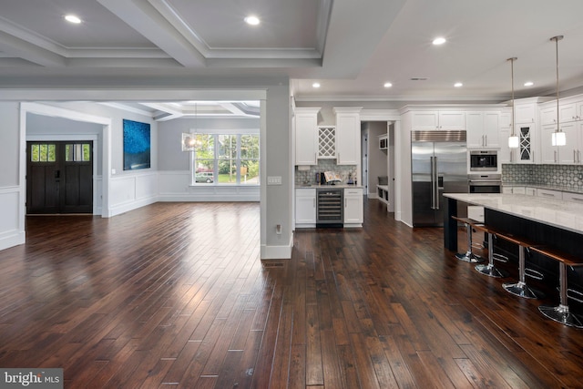living area featuring a wainscoted wall, beverage cooler, a healthy amount of sunlight, and dark wood-type flooring