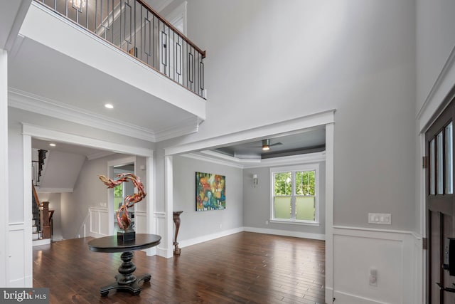 foyer entrance with wood-type flooring, ornamental molding, stairs, and wainscoting