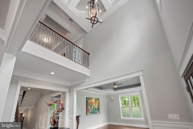 foyer with crown molding, ceiling fan with notable chandelier, stairs, recessed lighting, and a towering ceiling