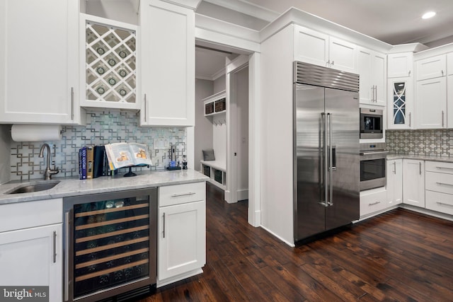 kitchen featuring decorative backsplash, wine cooler, white cabinetry, a sink, and stainless steel appliances