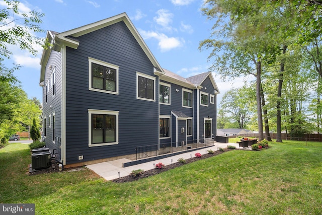 rear view of property featuring a lawn, a patio, fence, and central AC unit