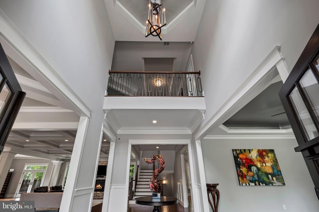 foyer entrance with stairs, an inviting chandelier, a high ceiling, ornate columns, and a premium fireplace