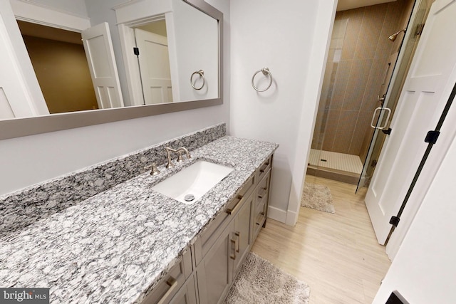 bathroom featuring a stall shower, vanity, baseboards, and wood finished floors