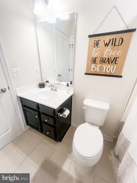 bathroom with toilet, tile patterned floors, baseboards, and vanity