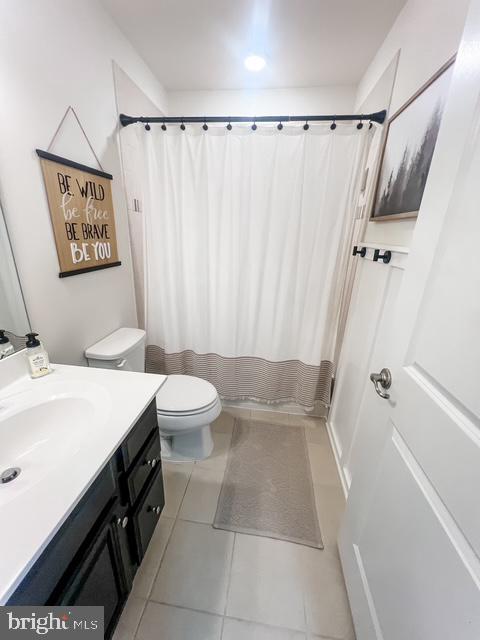 bathroom featuring vanity, a shower with shower curtain, tile patterned floors, and toilet