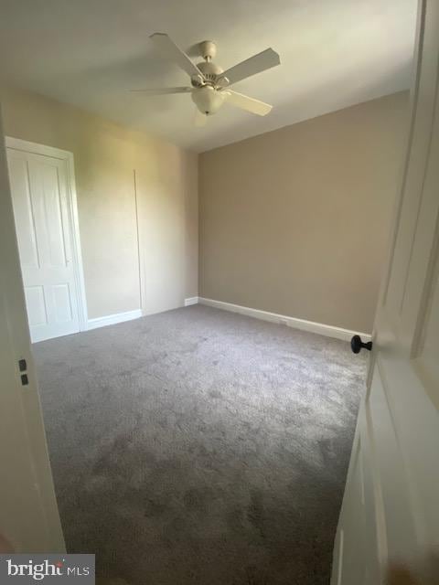carpeted spare room with baseboards and a ceiling fan