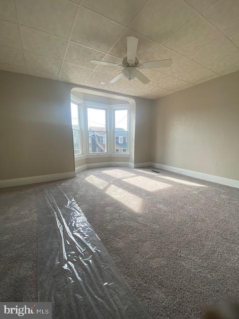empty room featuring baseboards, ceiling fan, and carpet floors