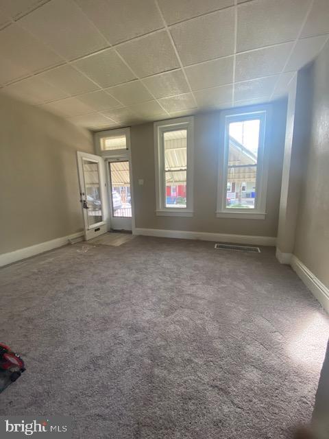 spare room with visible vents, a paneled ceiling, plenty of natural light, and carpet floors
