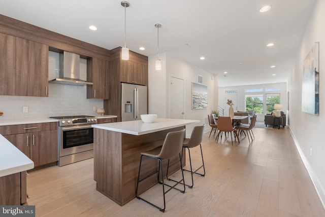 740 S Columbus Blvd Unit 74, Philadelphia, PA 19147 - kitchen with appliances with stainless steel finishes, wall chimney exhaust hood, a breakfast bar area, light countertops, and modern cabinets