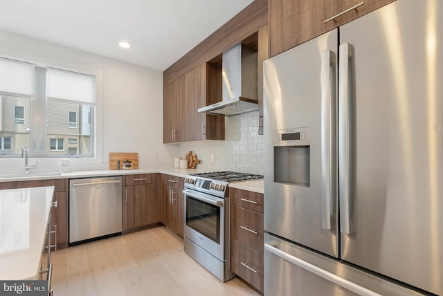 740 S Columbus Blvd Unit 74, Philadelphia, PA 19147 - kitchen with stainless steel appliances, wall chimney exhaust hood, light wood finished floors, light countertops, and backsplash