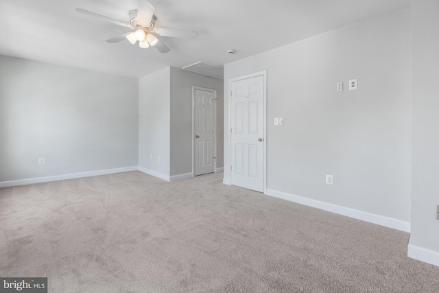 spare room with light colored carpet, attic access, baseboards, and ceiling fan