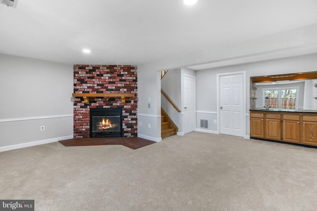 unfurnished living room with a fireplace, carpet, recessed lighting, visible vents, and stairway