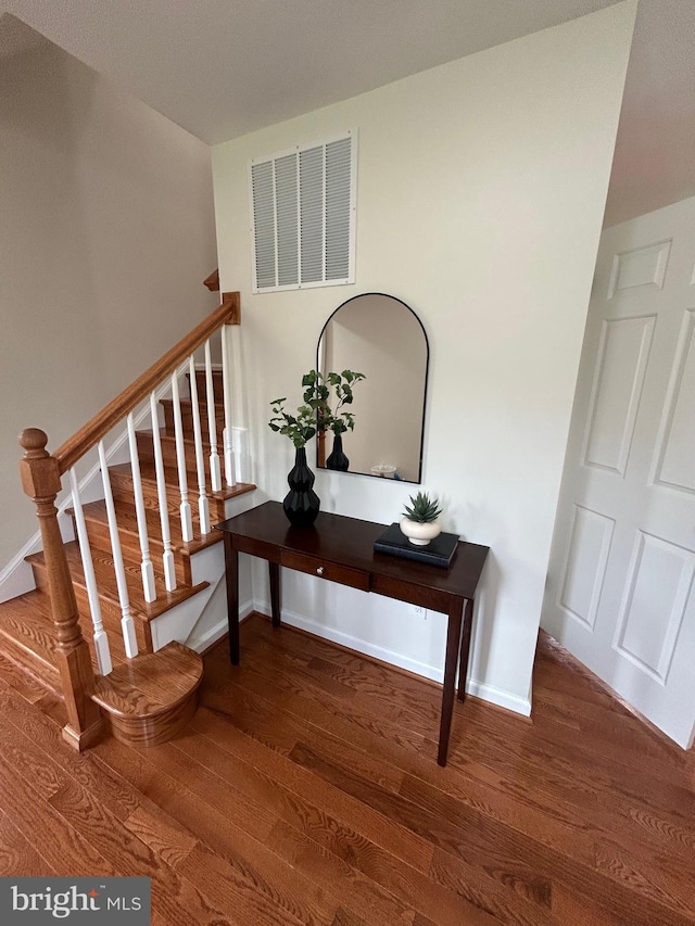 stairs with visible vents, wood finished floors, and baseboards