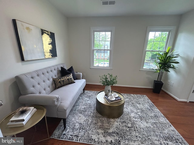 living area featuring a wealth of natural light, visible vents, wood finished floors, and baseboards