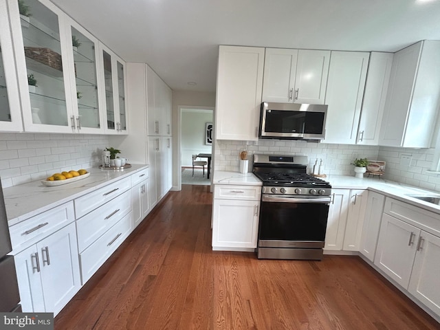 kitchen featuring dark wood finished floors, white cabinets, appliances with stainless steel finishes, and decorative backsplash