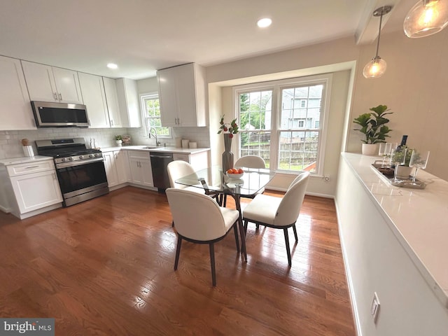 kitchen featuring a sink, stainless steel appliances, dark wood-style flooring, light countertops, and tasteful backsplash