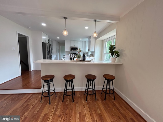 kitchen with a kitchen breakfast bar, white cabinetry, dark wood finished floors, and appliances with stainless steel finishes