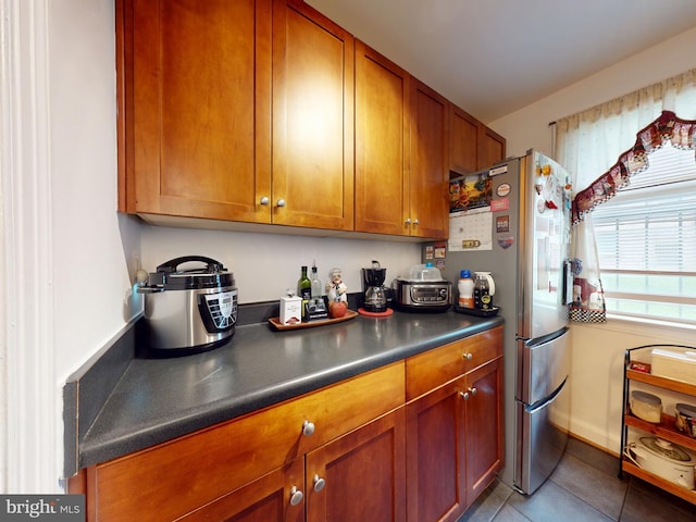 4408 1st Pl NE Unit 14, Washington, DC 20011 - kitchen with brown cabinetry, dark countertops, freestanding refrigerator, and tile patterned floors