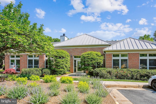 1704 Lake Shore Crest Dr Unit 32, Reston, VA 20190 - rear view of property with a standing seam roof, brick siding, a chimney, and metal roof