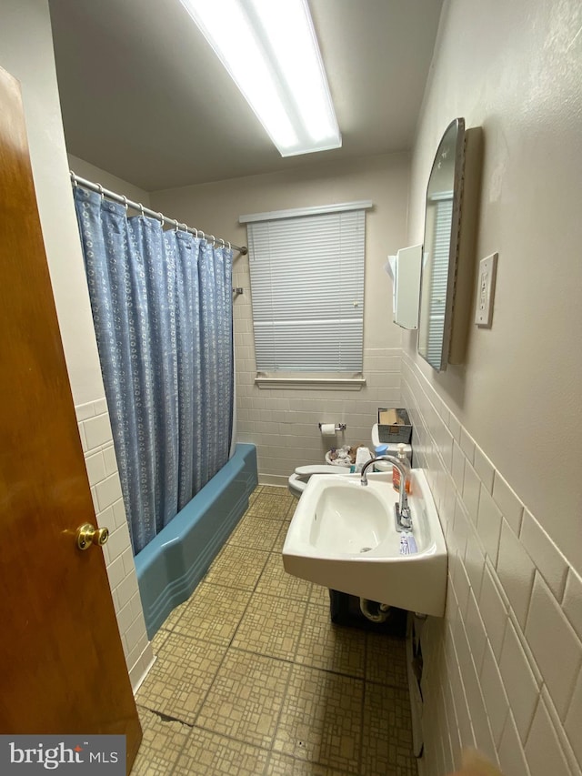 full bath featuring a sink, tile walls, toilet, and shower / bath combination with curtain