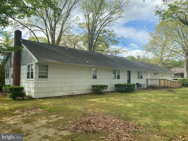 rear view of property featuring a chimney and a yard