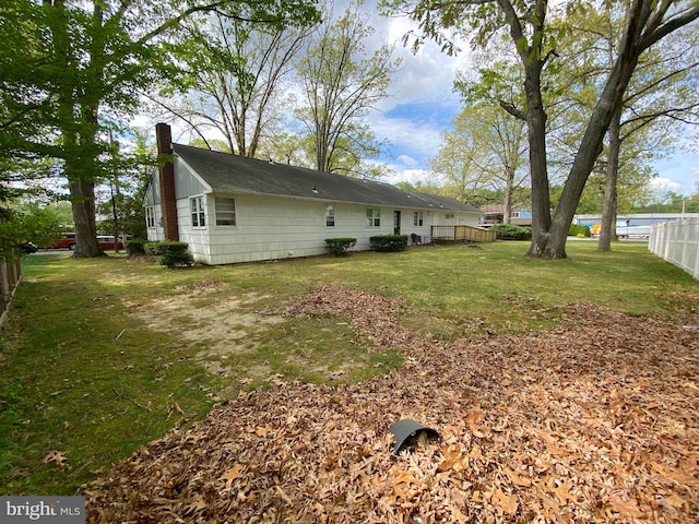 exterior space featuring fence, a chimney, and a yard