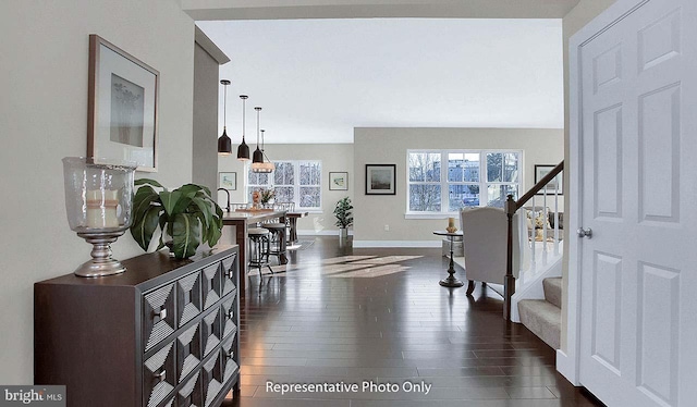 foyer entrance featuring baseboards, dark wood finished floors, and stairway