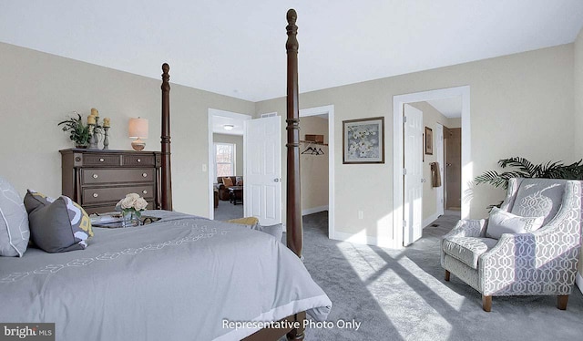 carpeted bedroom with baseboards, a walk in closet, and ensuite bathroom