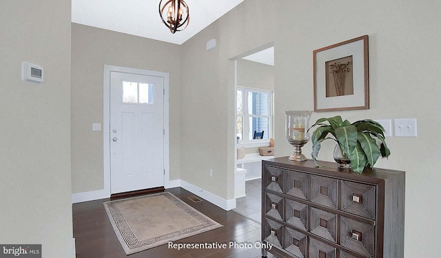 foyer entrance with an inviting chandelier, baseboards, and dark wood finished floors