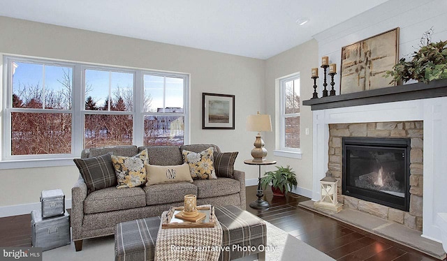living room featuring baseboards, a stone fireplace, and wood finished floors