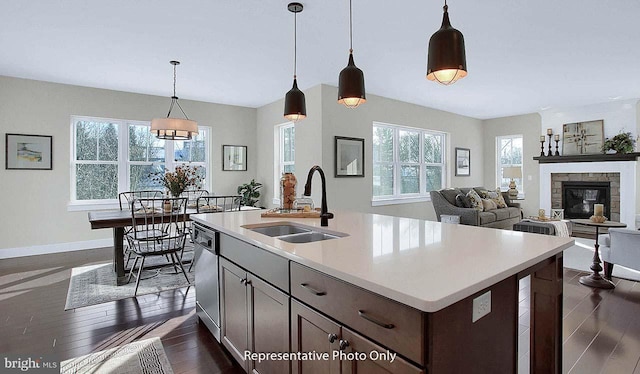 kitchen featuring stainless steel dishwasher, baseboards, dark wood-style floors, light countertops, and a sink