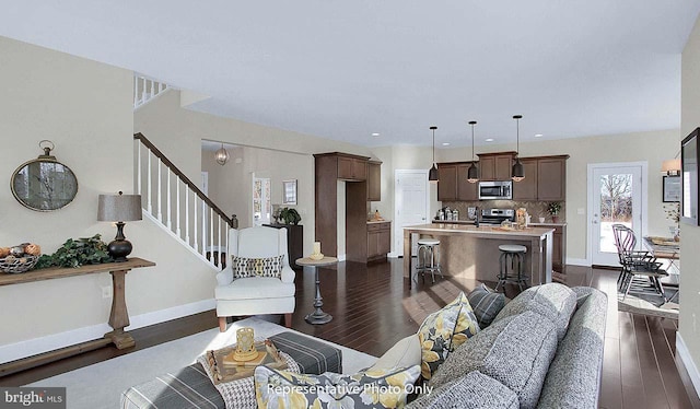 living area with dark wood-style flooring, baseboards, visible vents, and stairway