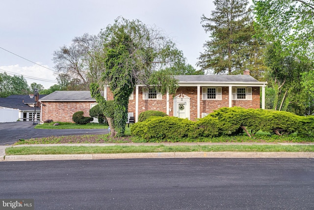 bi-level home with a chimney and brick siding