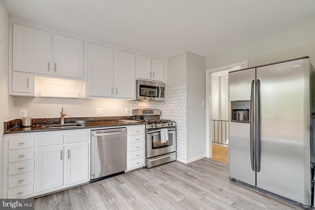 kitchen featuring a sink, appliances with stainless steel finishes, light wood finished floors, and white cabinetry